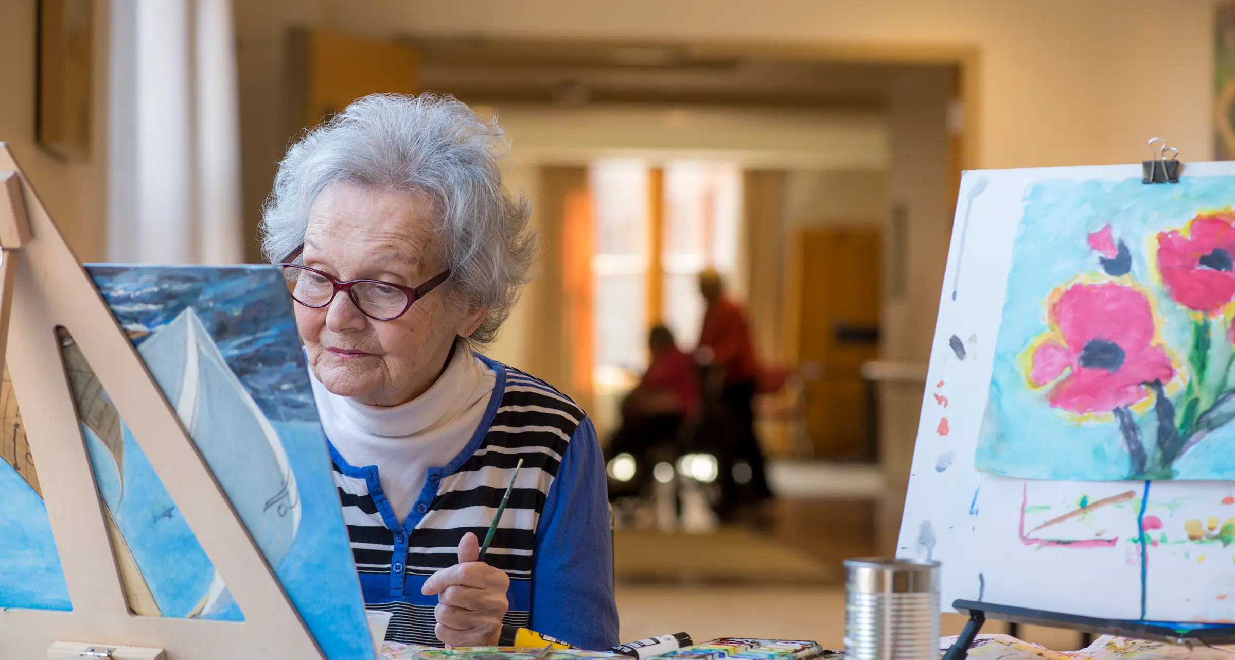 A woman painting on an easle with other artwork nearby