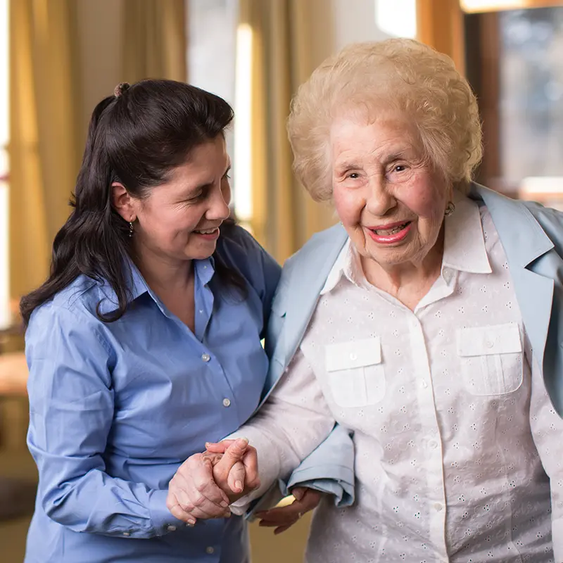 an older woman being helped by a younger woman in a sunny room