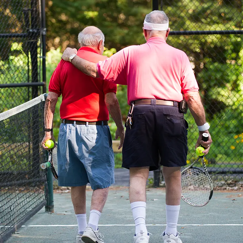 two male tennis players walking away from the camera, one arm around the other, as they walk off the court